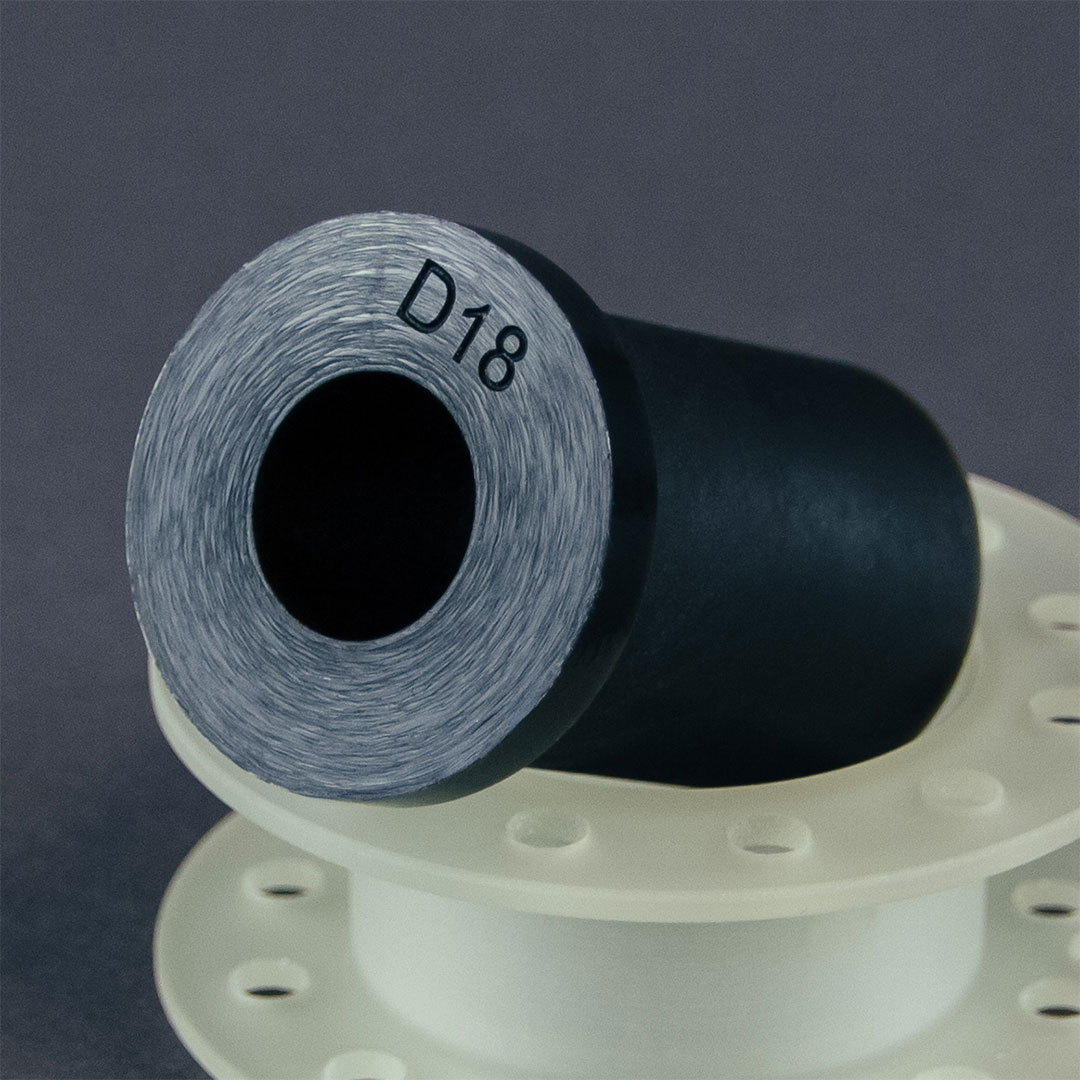 schwarzes CNC Drehteil mit einer Lasergravur liegt auf einem weiteren Drehteil aus PU