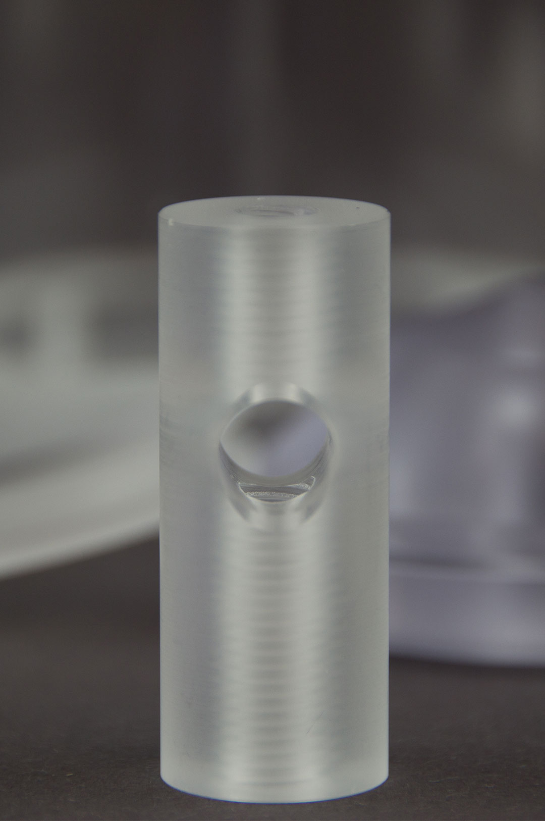 Ein stabförmiges Kunststoffbauteil aus PMMA mit ein Bohrloch in der Mitte