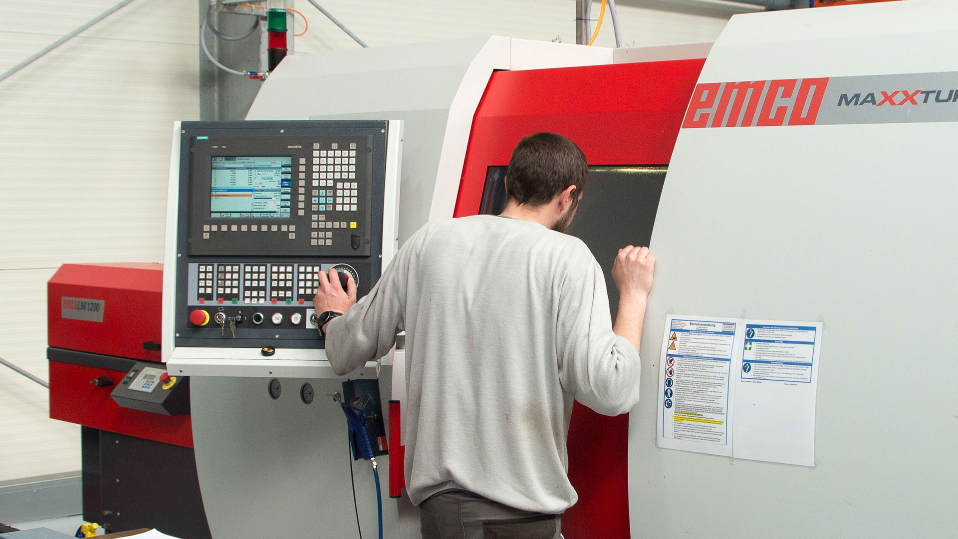 Ein Mitarbeiter blickt in eine CNC-Drehmaschine