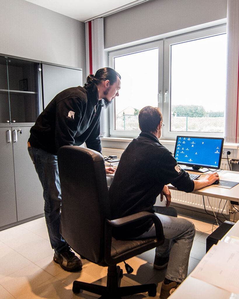 Einblick in die Büroarbeit. Monika Lampe sitzt am PC, neben ihr steht Sohn Sebastian Lampe